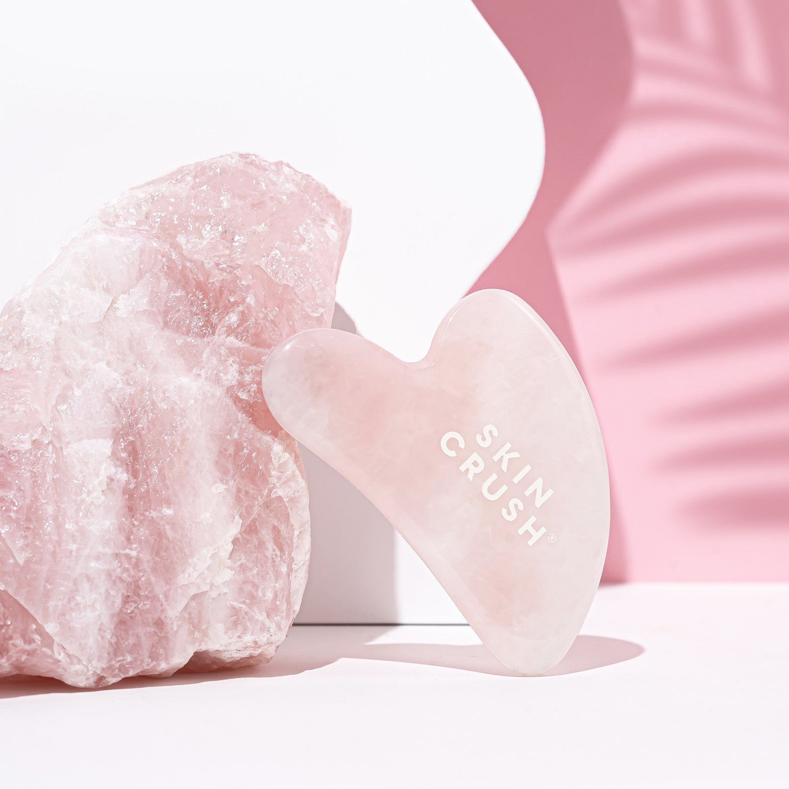 rose quartz gua sha large rose quartz crystal in background