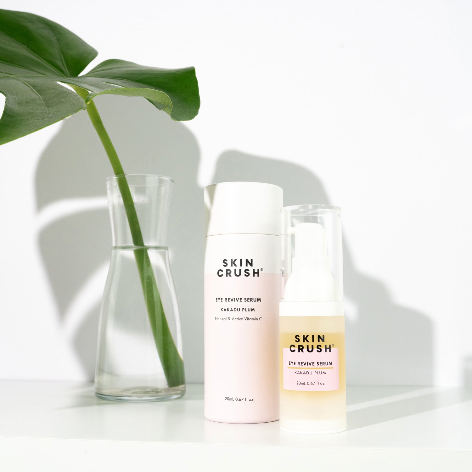 skin crush kakadu plum vitamin c serum potent active in pink packaging next to a vase with a monstera leaf in it in water
