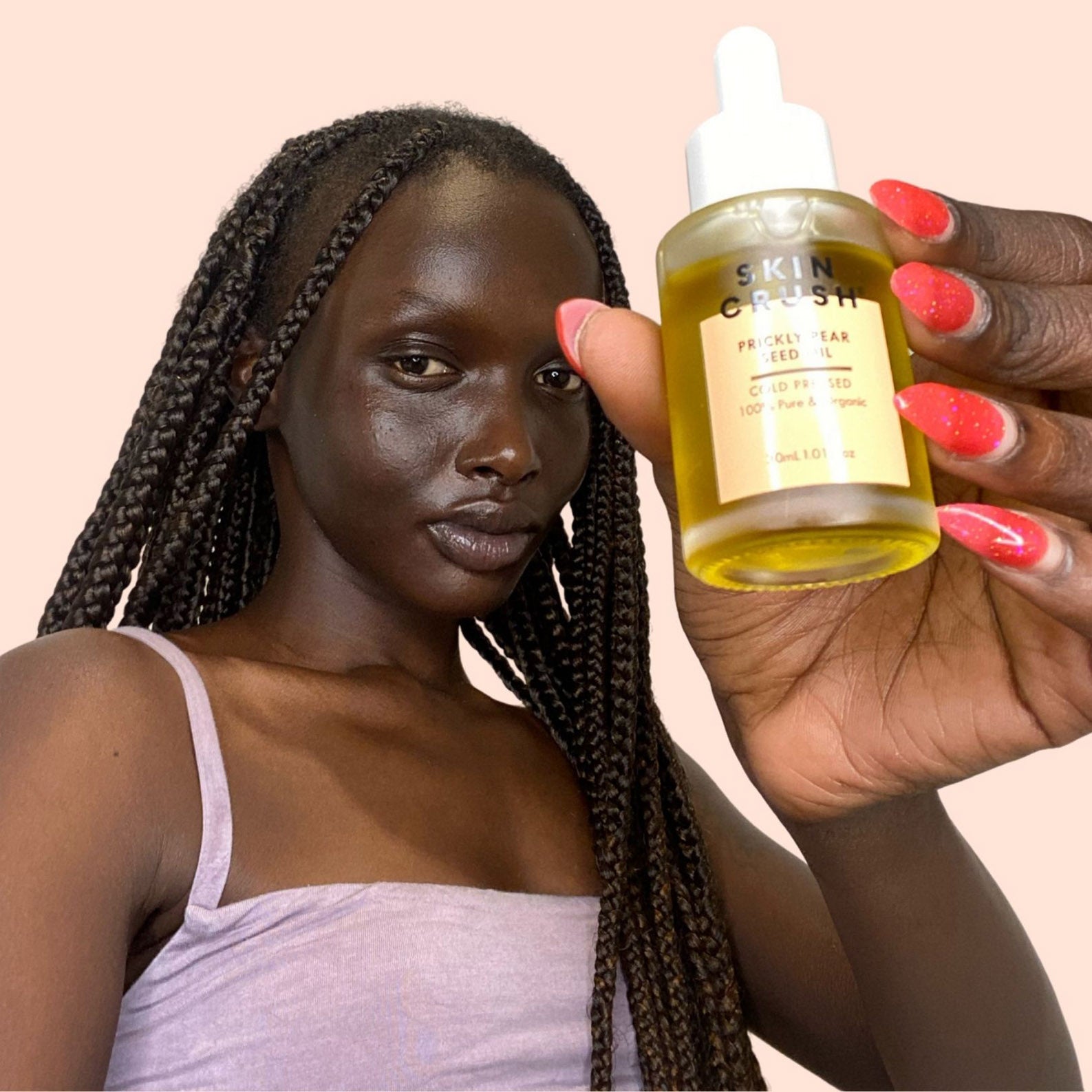 woman holding prickly pear seed oil beautiful african american woman with braids holding prickly pear seed oil in photo for skin crush on beige pink background